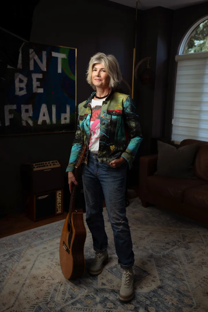 Catherine Harrison standing with her acoustic guitar