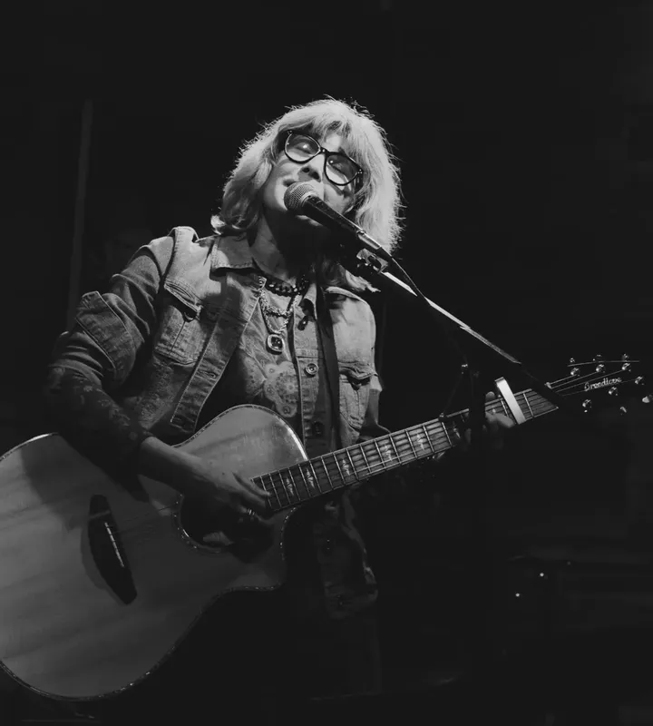 Catherine Harrison singing and playing acoustic guitar on stage