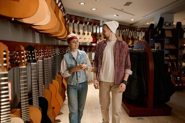 Two musicians talking as they walk through a guitar shop